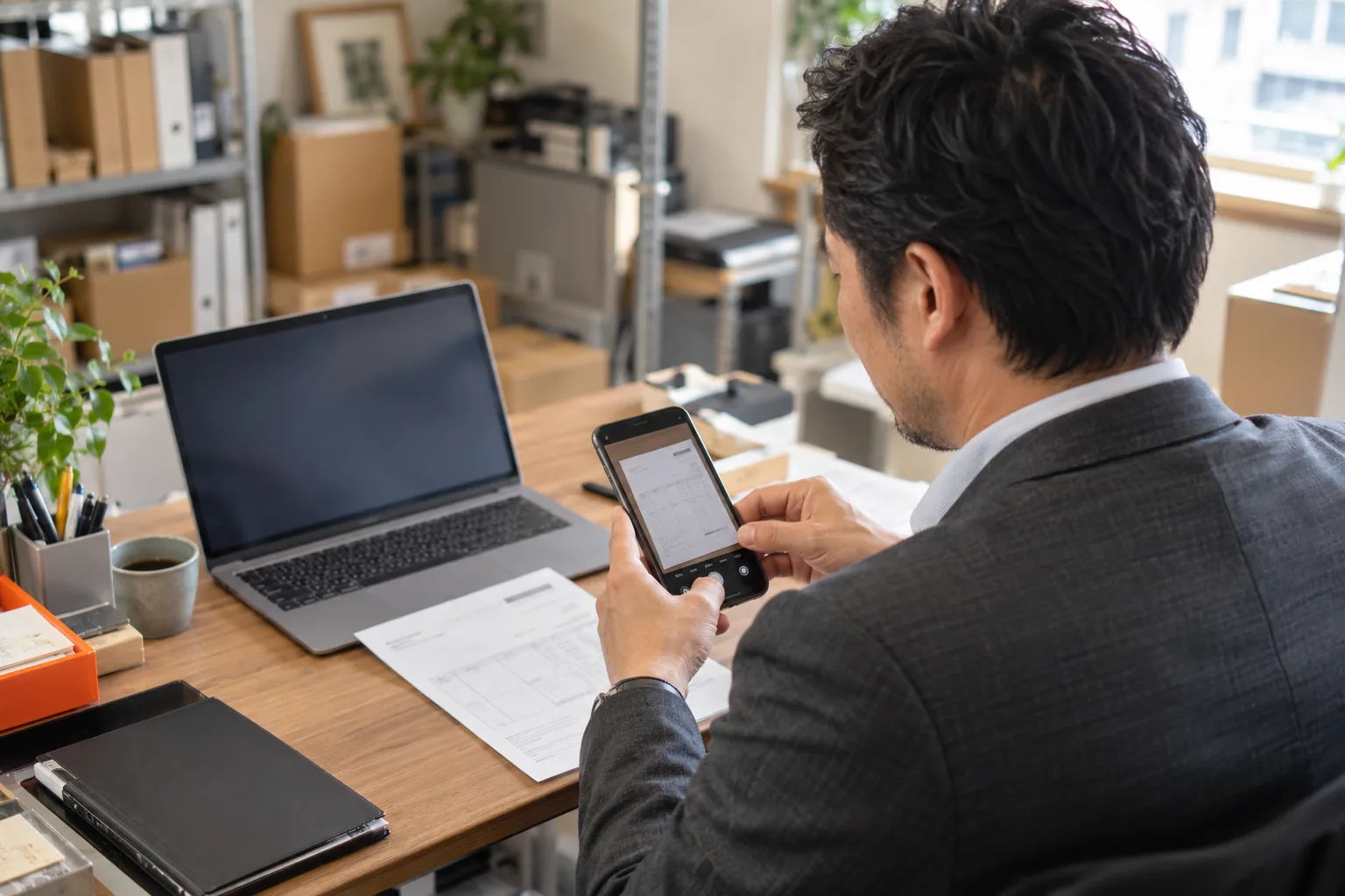 スマートフォンを確認しながら仕事をする経営者のイメージ